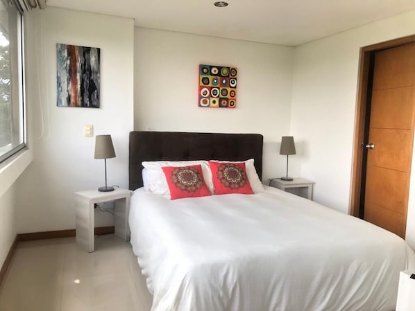 A neatly arranged bedroom with a large bed, two bedside tables, and a window.