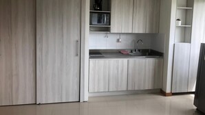 Une cuisine moderne avec des meubles de couleur bois clair, un plan de travail noir et un four à micro-ondes encastré.