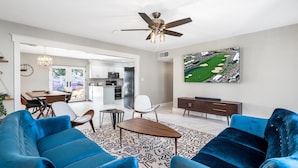 A spacious living room with a large blue sofa set, a wooden coffee table, and a ceiling fan. - Pool & Art Lover Oasis near Old Town w/ Mini Golf (Scottsdale)