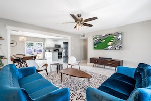 A spacious living room with a large blue sofa set, a wooden coffee table, and a ceiling fan. - Pool & Art Lover Oasis near Old Town w/ Mini Golf (Scottsdale)