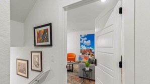A hallway leading to a living area with a sofa, a coffee table, and a painting on the wall. - Art-Lover’s Suite - Minutes to Crystal Bridges (Bentonville)