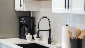 A modern kitchen with a black faucet, white countertop, and a coffee machine. - Bentonville Art Suite • Near Crystal Bridges & Osage Park (Bentonville)