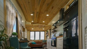 Eine gemütliche Küche mit Holzböden, einem schwarzen Kühlschrank und einer Essecke mit blauem Stuhl und einer Couch.