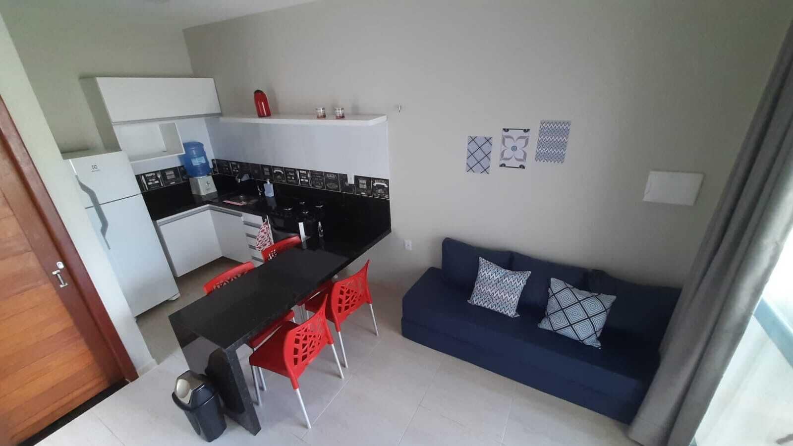 A compact living space with a kitchenette, dining area, and a sofa with patterned cushions.