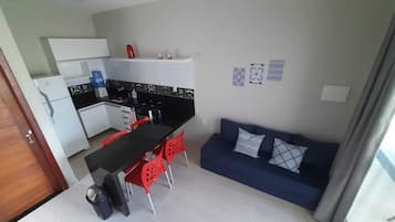 A compact living space with a kitchenette, dining area, and a sofa with patterned cushions.