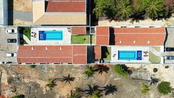 An aerial view of a residential area with multiple houses, a swimming pool, and palm trees.