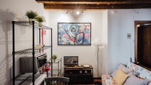 Una habitación con techo de madera, un cuadro, un extintor, un televisor y un sofá.