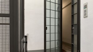 A hallway with a glass door and a metal gate, leading to a tiled area. - Ricasoli Apartment - Two Bedroom Apartment, Sleeps 4 (Firenze)
