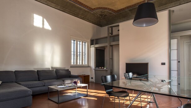 A modern living room with a sofa, a glass dining table, and a fireplace. - Ricasoli Apartment - Two Bedroom Apartment, Sleeps 4 (Firenze)
