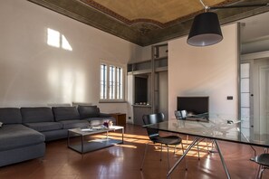 A modern living room with a sofa, a glass dining table, and a fireplace. - Ricasoli Apartment - Two Bedroom Apartment, Sleeps 4 (Firenze)