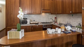 A kitchen with wooden cabinets, a central island, a stove, a microwave, and various kitchen items. - Proconsolo - Two Bedroom Apartment, Sleeps 4 (Firenze)