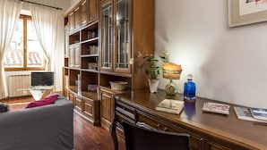 A room with a wooden desk, a bookshelf, a radiator, a window with curtains, and a framed picture on the wall. - Proconsolo - Two Bedroom Apartment, Sleeps 4 (Firenze)
