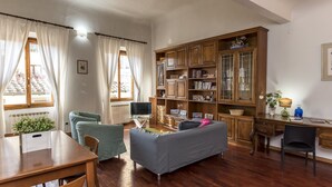 A cozy living room with a wooden cabinet, a sofa, a dining table, and a TV. - Proconsolo - Two Bedroom Apartment, Sleeps 4 (Firenze)