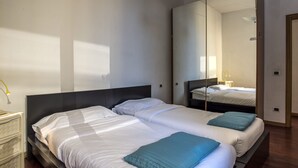 A hotel room with two beds, a large mirror, and a bedside table with a lamp. - Proconsolo - Two Bedroom Apartment, Sleeps 4 (Firenze)