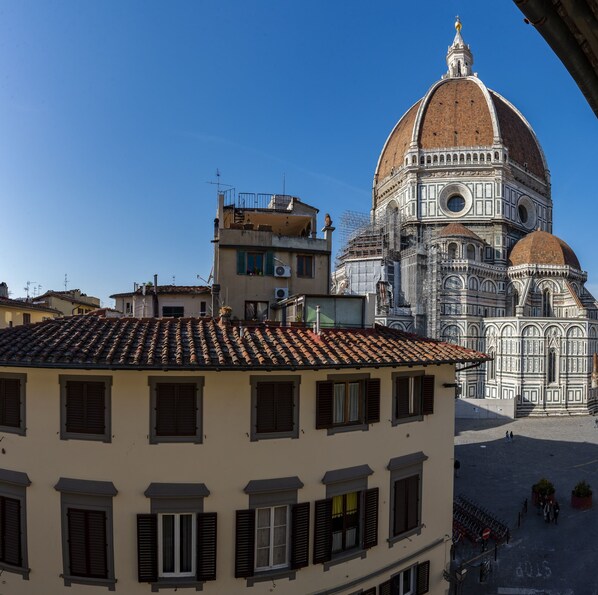 A building with a tiled roof and multiple windows, in front of a large historical structure with a dome.