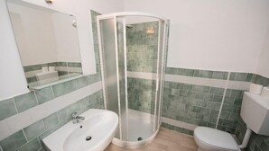 A bathroom with a glass-enclosed shower, a sink, and a toilet.