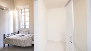 Une chambre à coucher avec un lit, un radiateur, une fenêtre et une armoire.