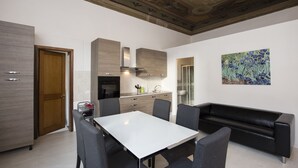 Une cuisine moderne avec un coin repas, comprenant une table blanche, des chaises grises et un canapé noir.