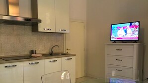A modern kitchen with a glass dining table, a built-in oven, and a television on a cabinet. - Campidoglio T - One Bedroom Apartment, Sleeps 2 (Firenze)