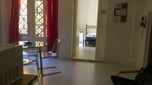 A room with a bed, a desk with a chair, a radiator, and a door leading to another room. - Campidoglio T - One Bedroom Apartment, Sleeps 2 (Firenze)