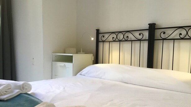A neatly made bed with white linens, a bedside table with a lamp, and a white wardrobe. - Campidoglio T - One Bedroom Apartment, Sleeps 2 (Firenze)