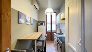 A compact kitchen with a wooden table, chairs, a microwave, and a sink. - Fortezza Fourth Floor 4 Pax (Firenze)