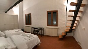 A bedroom with two beds, a small table, and a wooden staircase. - Alfani second floor - Three Bedroom Apartment, Sleeps 5 (Firenze)