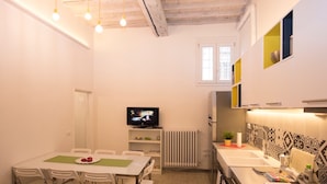 Ein kompakter Wohnbereich mit Essplatz, Küchenzeile und Fernseher.