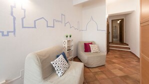 A modern interior with two sofas, a white shelf with plants, and a tiled floor. - Faenza double - One Bedroom Apartment, Sleeps 2 (Firenze)