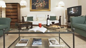 Un salon avec une table basse en verre, un canapé, un téléviseur et un tableau accroché au mur.