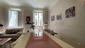 A living room with a long table, a sofa, and a TV. - Battistero Apartment (Firenze)