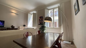 A dining area with a wooden table, red chairs, a tall floor lamp, and a small Christmas tree. - Battistero Apartment (Firenze)