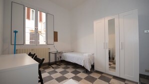 Una stanza piccola e pulita con un letto, una scrivania e un armadio.
