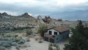 A small, modern two-story building with a balcony, surrounded by a desert landscape with sparse vegetation and rocky formations. - >>MAGICAL property on 5 acres in the Alabama Hills (Lone Pine)