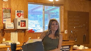 A wooden interior with a window, a first aid kit, and an AED sign.
