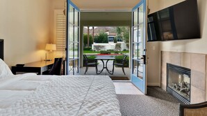 Une chambre d’hôtel avec un lit, un bureau doté d’une lampe, un téléviseur fixé au mur et une cheminée.