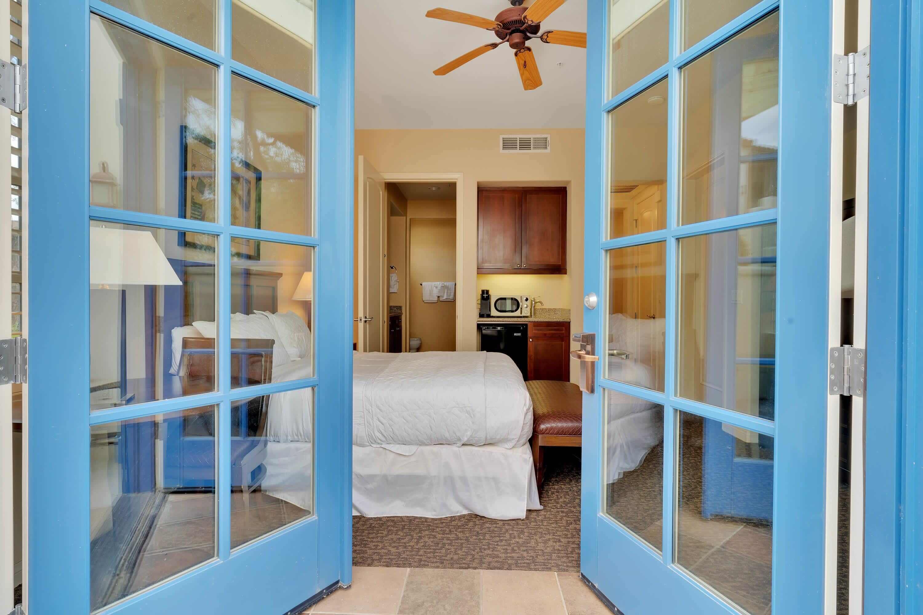 Une chambre d’hôtel équipée d’un lit, d’une chaise, d’un bureau, d’un ventilateur de plafond et d’une kitchenette.