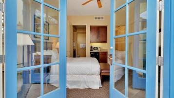 Une chambre d’hôtel équipée d’un lit, d’une chaise, d’un bureau, d’un ventilateur de plafond et d’une kitchenette.