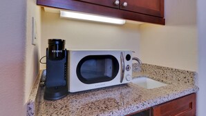 Una kitchenette equipada con microondas, cafetera y lavamanos.