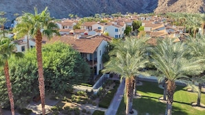 Un barrio residencial con casas, palmeras y montañas al fondo.