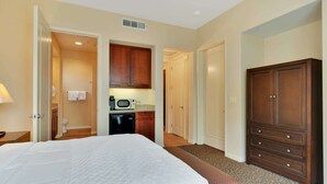 Habitación de hotel con cama, kitchenette, armario y baño.