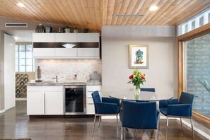 Une cuisine moderne avec des meubles blancs, une cuisinière en acier inoxydable et un coin repas avec des chaises bleues et une table ronde.