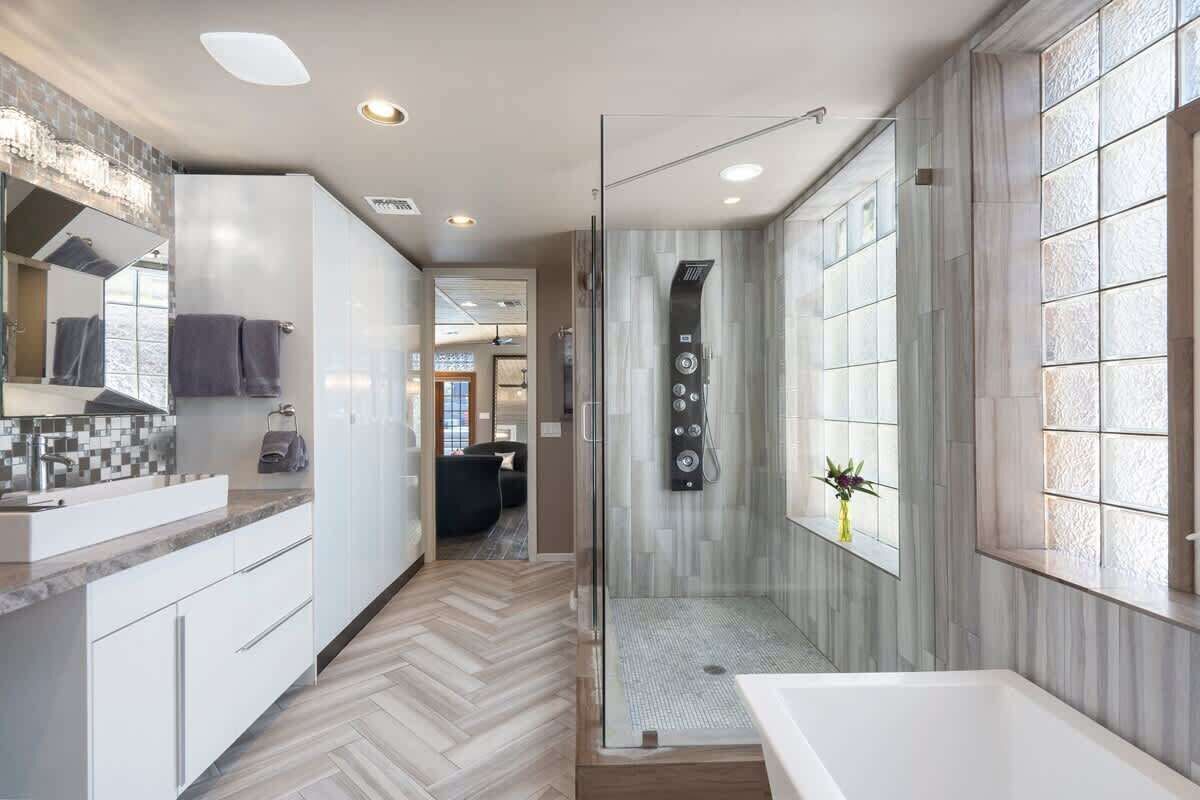 Une salle de bain moderne dotée d’une douche à parois de verre, d’une grande baignoire et d’un meuble-lavabo avec un miroir et un évier.