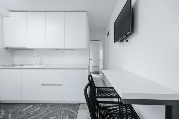 Een koelkast, een kookplaat, een waterkoker, kookgerei, borden en bestek