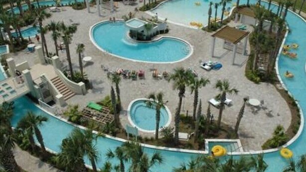 A large, winding pool with multiple sections, surrounded by palm trees and lounge areas. - Destin Festival!!  Sept 24 - 28 Available (Fort Walton Beach)