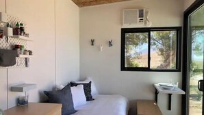 A bedroom with a bed, bedside table, and a window with a view of trees.