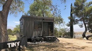 A small, single-story cabin with a front porch and a sliding door.