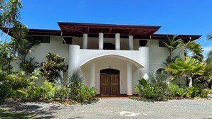 Un edificio con fachada blanca, puerta de madera y zona de acceso cubierta.