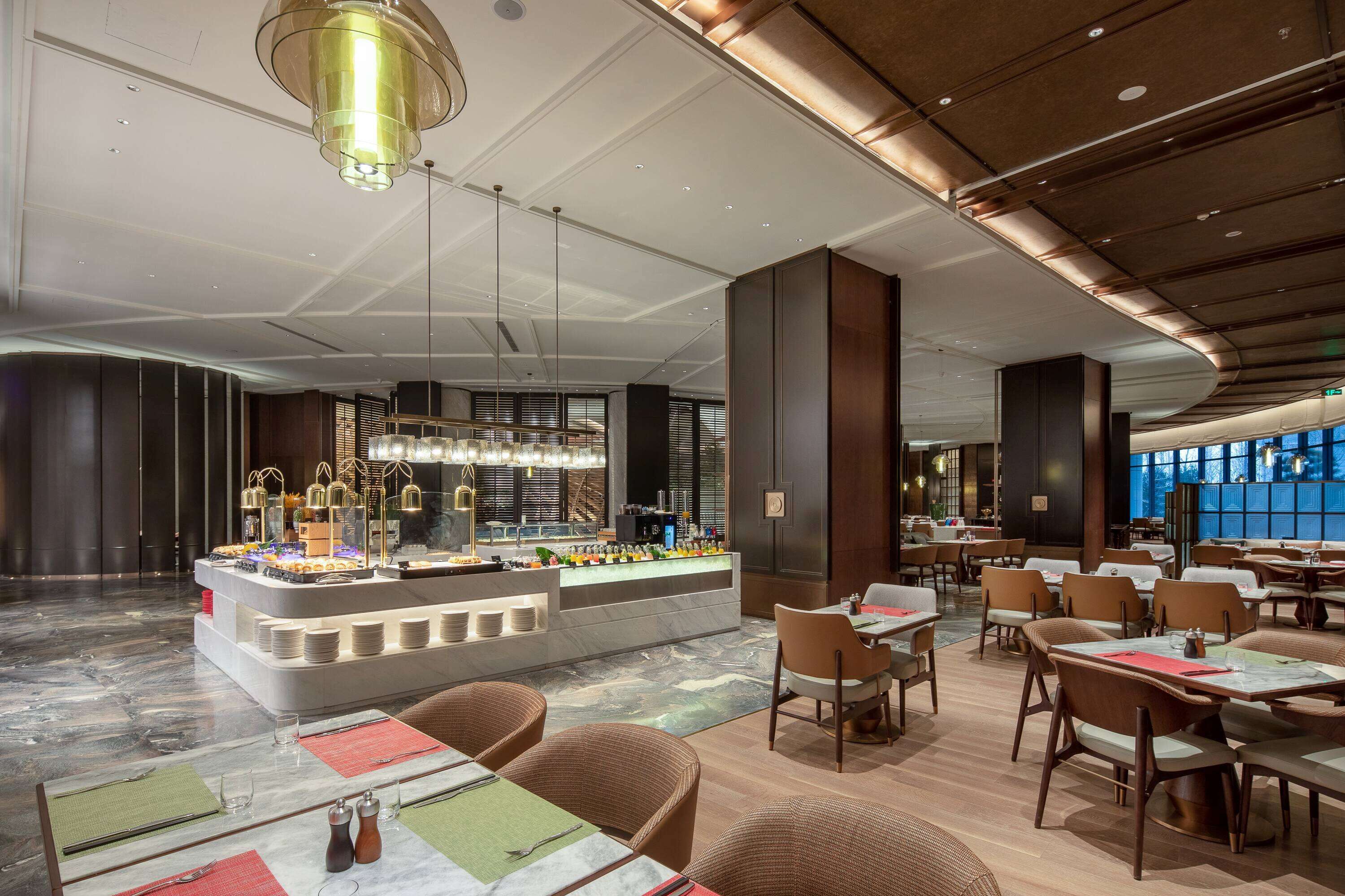 Un restaurante moderno con barra central, varias mesas de comedor y suelo de mármol.