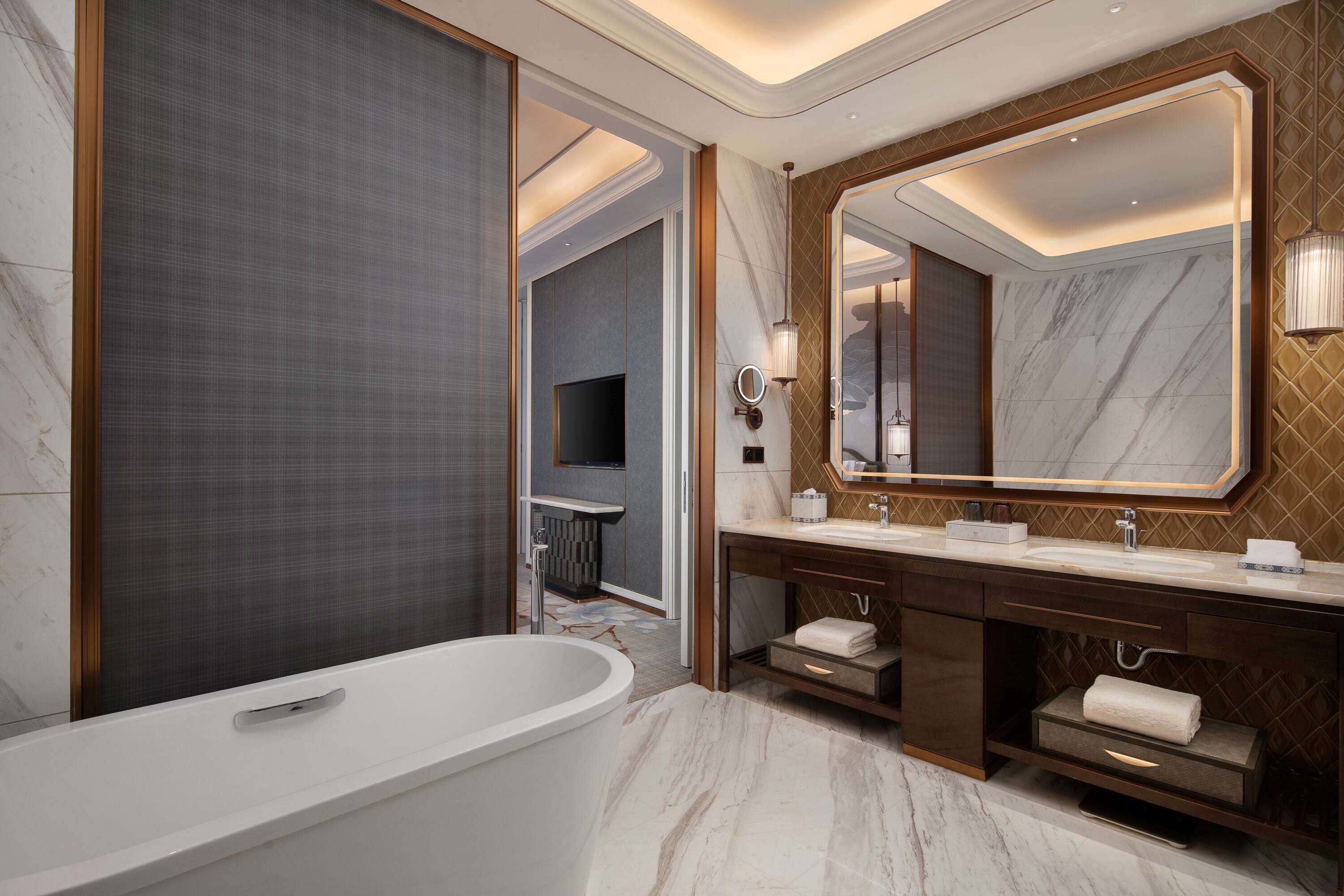 A modern bathroom with a freestanding bathtub, a large mirror, and a vanity with a sink and towel rack.